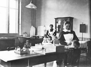 Krankenpflegerinnen mit stationär aufgenommenen Kindern im Zimmer der Kinderabteilung im ersten Obergeschoss, 1909